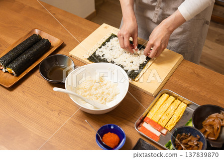 Close-up of a woman's hands making Ehomaki (lucky direction sushi roll). Close-up of a woman's hands making Ehomaki (lucky direction sushi roll). 137839870