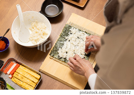 Close-up of a woman's hands making Ehomaki (lucky direction sushi roll). 137839872