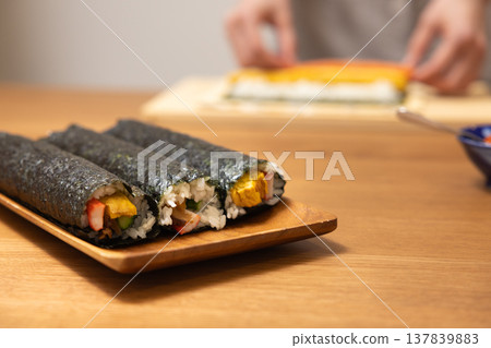 Close-up of a woman's hands making Ehomaki (lucky direction sushi roll). 137839883