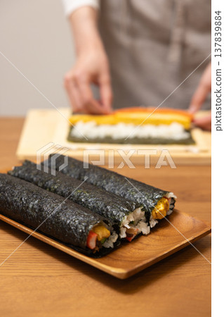 Close-up of a woman's hands making Ehomaki (lucky direction sushi roll). Close-up of a woman's hands making Ehomaki (lucky direction sushi roll). 137839884