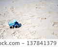 A blue toy dump truck driving on the beach 137841379