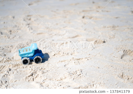 A blue toy dump truck driving on the beach 137841379