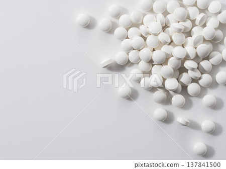 White tablets and supplements scattered against a white background. 137841500