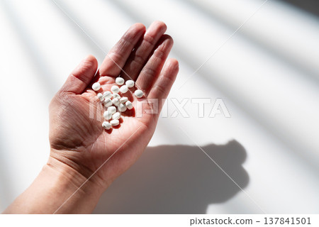 A large number of white tablets/supplements placed in the palm of my hand A large number of white tablets/supplements placed in the palm of my hand 137841501