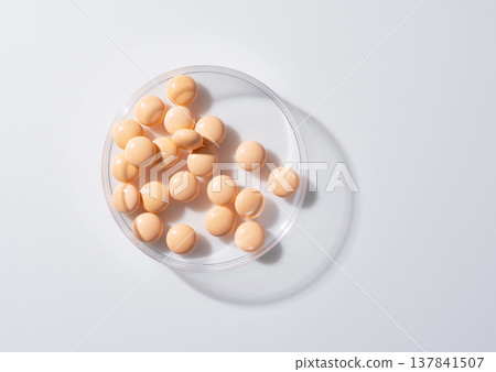 白色背景上的培養皿中放著橘色的藥片/補充劑。 白色背景上的培養皿中放著橘色的藥片/補充劑。 137841507