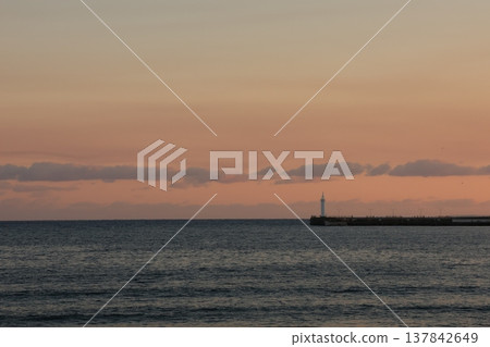The scenery around Enoshima Island, bathed in orange light as seen from Koshigoe Beach at sunset. 137842649