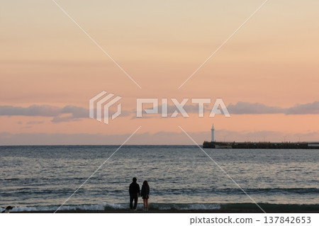 The scenery around Enoshima Island, bathed in orange light as seen from Koshigoe Beach at sunset. The scenery around Enoshima Island, bathed in orange light as seen from Koshigoe Beach at sunset. 137842653