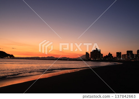 The scenery around Enoshima Island, bathed in orange light as seen from Koshigoe Beach at sunset. The scenery around Enoshima Island, bathed in orange light as seen from Koshigoe Beach at sunset. 137842663