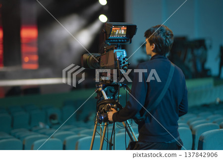 Young student cameraman operating professional TV camera in theater with copy space 137842906