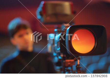 Young filmmaker student operating broadcasting camera in concert hall with copy space Young filmmaker student operating broadcasting camera in concert hall with copy space 137842908