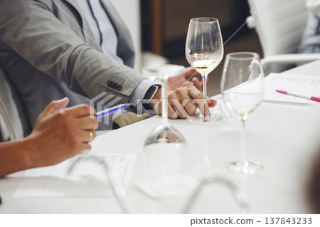 Wine experts association, sommelier school, professional development. Sommelier wearing in casucal jacket tasting white wine from glass, analysing its taste, color, smell and acidity level.  137843233