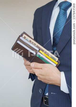 A businessman takes out his wallet | A wallet containing Japanese banknotes and cards. A businessman takes out his wallet | A wallet containing Japanese banknotes and cards. 137843569