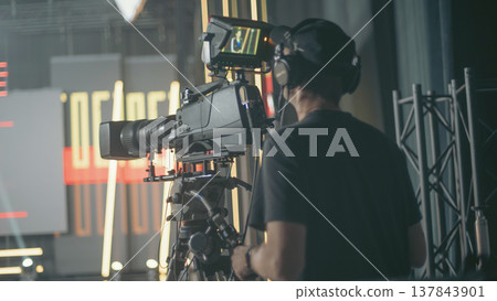 Professional cameraman filming breaking news in live TV studio with copy space 137843901