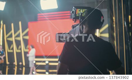Cameraman working in professional TV studio during live broadcast with copy space Cameraman working in professional TV studio during live broadcast with copy space 137843902
