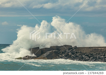 High Energy Ocean Wave Crashing Against Stone Pier with Huge Water Splash and Copy Space High Energy Ocean Wave Crashing Against Stone Pier with Huge Water Splash and Copy Space 137844269