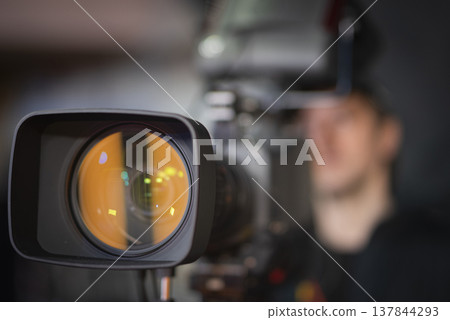 Professional broadcast camera lens in news studio with amber reflection and copy space Professional broadcast camera lens in news studio with amber reflection and copy space 137844293