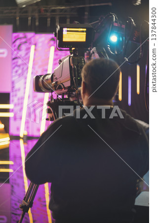 Professional cameraman in news studio with broadcast camera and copy space Professional cameraman in news studio with broadcast camera and copy space 137844300