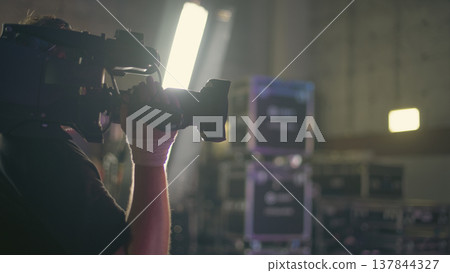 Professional cameraman working with heavy video camera in studio with copy space 137844327