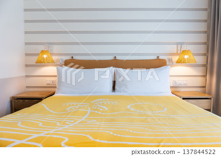 Bedroom headboard with white pillows, yellow blanket and warm bedside lamp and on off switch with USB charger. Bedroom headboard with white pillows, yellow blanket and warm bedside lamp and on off switch with USB charger. 137844522
