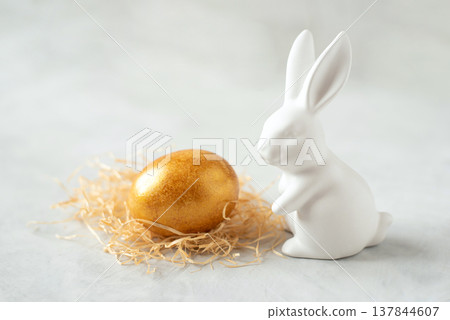 Easter greeting background with white Easter bunny and golden egg Easter greeting background with white Easter bunny and golden egg 137844607