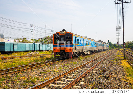 Diesel rail is a fast intercity train in Thailand with many tracks and traffic lights and freight cars in the background. 137845125
