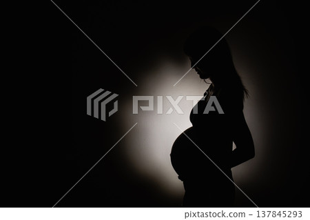 Pregnant woman's shadow with light in the center in room background. Concept photography copy space. Pregnant woman's shadow with light in the center in room background. Concept photography copy space. 137845293