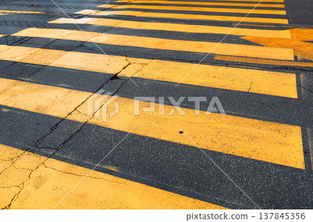 Crosswalk with yellow lines and shadow patterns on the ground during daytime Crosswalk with yellow lines and shadow patterns on the ground during daytime 137845356