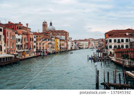 Canal flows through buildings in Venice under a cloudy sky in the afternoon light 137845392