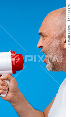 Man speaks into a megaphone against a bright blue background during a public event Man speaks into a megaphone against a bright blue background during a public event 137845470