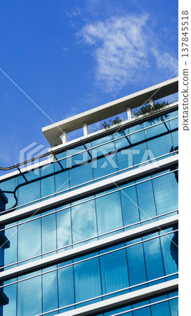 View of a modern building with glass windows under a clear blue sky on a sunny day 137845518