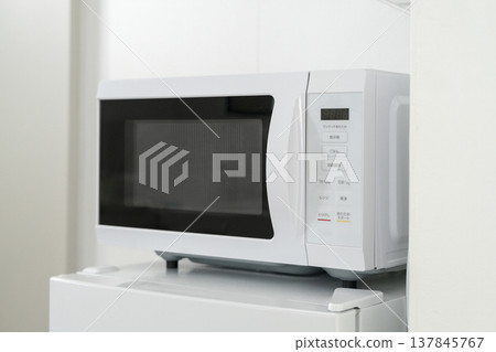 A microwave oven placed on top of the refrigerator 137845767