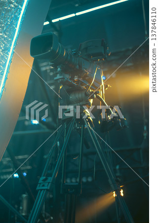 Professional Broadcasting Camera on Tripod in Cinematic Teal and Orange Lighting with copy space 137846110