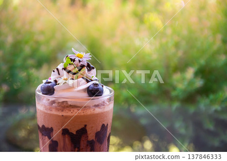 Closeup of beautiful chocolate milk coffee decorated with flowers, blueberries and cream cheese on a wooden table. Copy space background Closeup of beautiful chocolate milk coffee decorated with flowers, blueberries and cream cheese on a wooden table. Copy space background 137846333