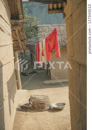 Traditional Mud House Courtyard in Rural India with Colorful Laundry and Copy Space 137848010