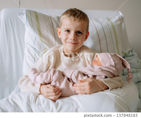 Older brother meeting newborn sibling for the first time. Concept of family bonding, childhood emotions and growing family. Older brother meeting newborn sibling for the first time. Concept of family bonding, childhood emotions and growing family. 137848183