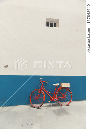 Red vintage bicycle parked against blue and white minimalist wall with vast copy space 137848640