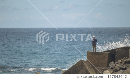 Senior man fishing in the blue ocean from rocky coast with copy space background for text Senior man fishing in the blue ocean from rocky coast with copy space background for text 137848642