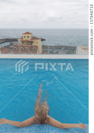 Relaxed woman in rooftop infinity pool with ocean and city view with copy space in sky Relaxed woman in rooftop infinity pool with ocean and city view with copy space in sky 137848718