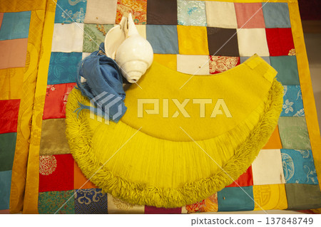 Tibetan Buddhist Ritual Conch Shell and Gelugpa Yellow Hat on Patchwork Altar with Copy Space 137848749