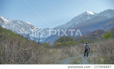 Female Hiker with Backpack Looking at Snowy Mountain Glacier with Copy Space 137848807