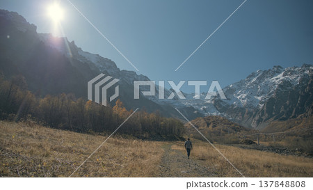 Male Hiker Walking Towards Snowy Mountains and Glacier with Copy Space 137848808