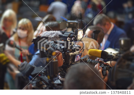 Professional Video Camera Filming Crowded Press Conference with Copy Space for News Concept Professional Video Camera Filming Crowded Press Conference with Copy Space for News Concept 137848811