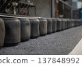 Row of black rubber tire buffers for safety on asphalt 137848992