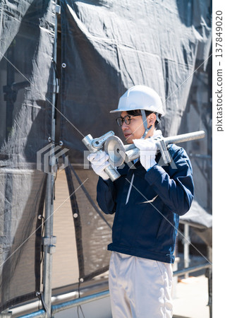 男性工作人員在建築工地進行鷹架拆卸和組裝工作。 男性工作人員在建築工地進行鷹架拆卸和組裝工作。 137849020