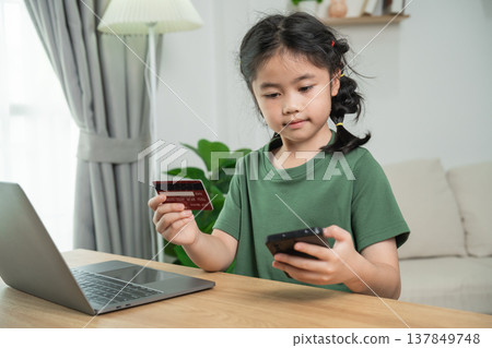 Young girl using smartphone and credit card for online shopping in cozy indoor environment, focus on technology and convenience for kids Young girl using smartphone and credit card for online shopping in cozy indoor environment, focus on technology and convenience for kids 137849748