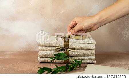 Female Hand Adjusting Velvet Ribbon On Stack Of Linen Napkins For Rustic Wedding Decor 137850223