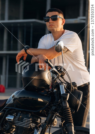 Standing and posing. Man is outdoors with his motorcycle Standing and posing. Man is outdoors with his motorcycle 137850354