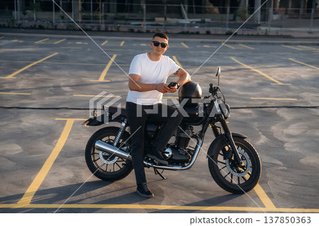 Smartphone is in hands. Man is outdoors with his motorcycle Smartphone is in hands. Man is outdoors with his motorcycle 137850363