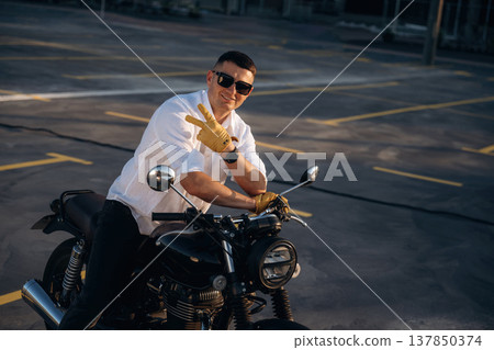 Happy, smiling and showing hand gesture. Man is outdoors with his motorcycle Happy, smiling and showing hand gesture. Man is outdoors with his motorcycle 137850374