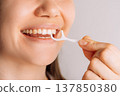 Woman using floss pick between teeth, close up oral care routine 137850380